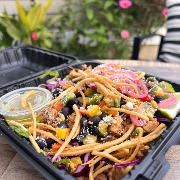 Flyin Taco's vibrant Mexican salad with chicken, black beans, mango, and crispy tortilla strips.