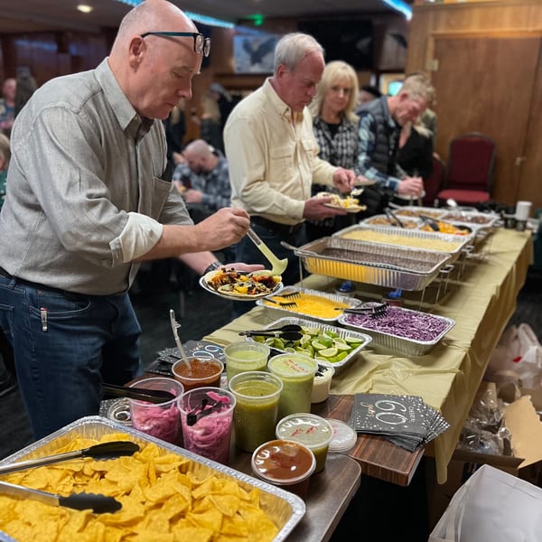 Guests at Flyin Taco's Mexican buffet, serving themselves tacos, chips, and various salsas.